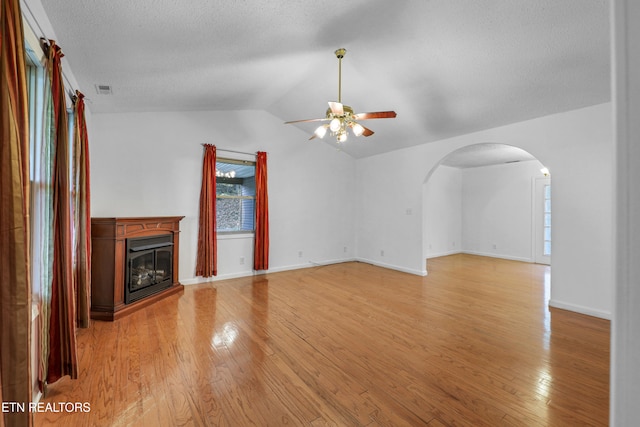 unfurnished living room with light hardwood / wood-style flooring, a textured ceiling, ceiling fan, and vaulted ceiling