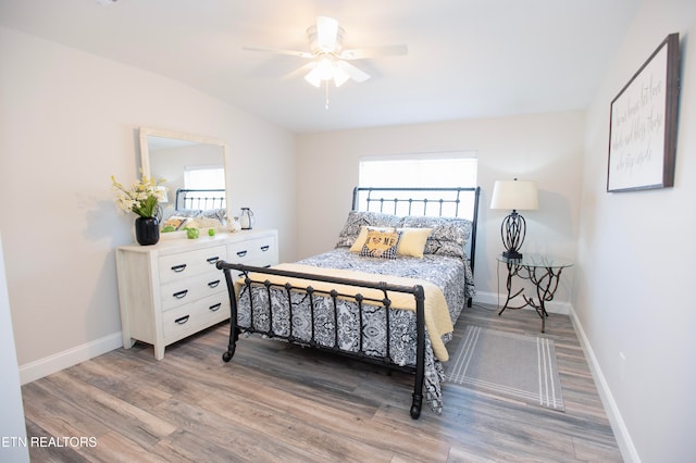 bedroom with ceiling fan, wood-type flooring, and vaulted ceiling