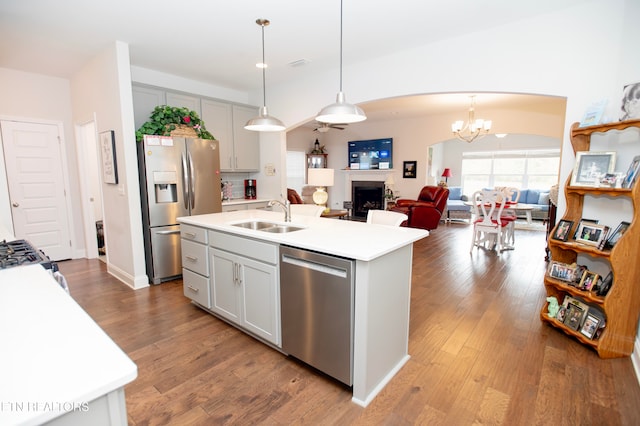 kitchen with sink, hanging light fixtures, stainless steel appliances, an island with sink, and hardwood / wood-style flooring