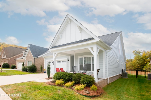 view of front of home featuring a porch, central AC, a garage, and a front lawn