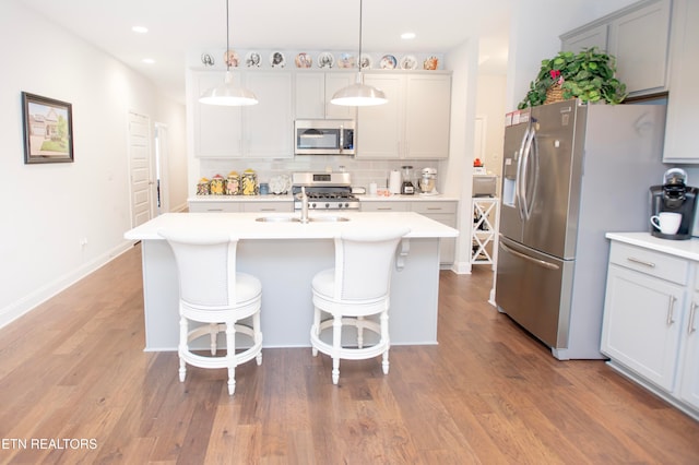 kitchen featuring decorative backsplash, decorative light fixtures, stainless steel appliances, and light hardwood / wood-style floors