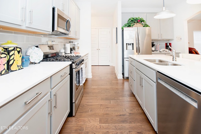 kitchen featuring tasteful backsplash, stainless steel appliances, sink, decorative light fixtures, and light hardwood / wood-style floors