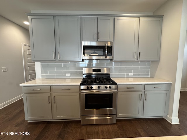 kitchen featuring appliances with stainless steel finishes, tasteful backsplash, gray cabinets, and dark wood-type flooring