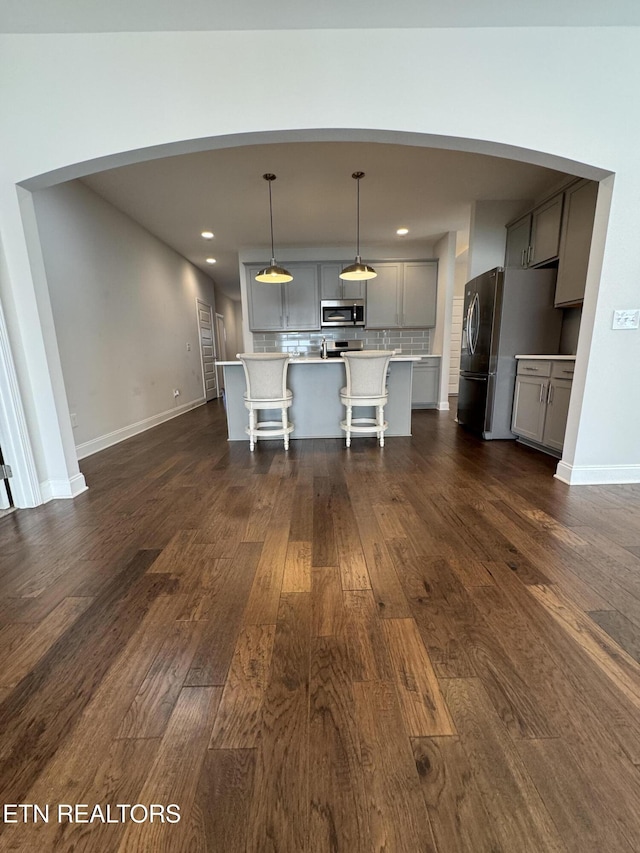 kitchen with dark hardwood / wood-style flooring, stainless steel appliances, gray cabinets, a kitchen island, and hanging light fixtures