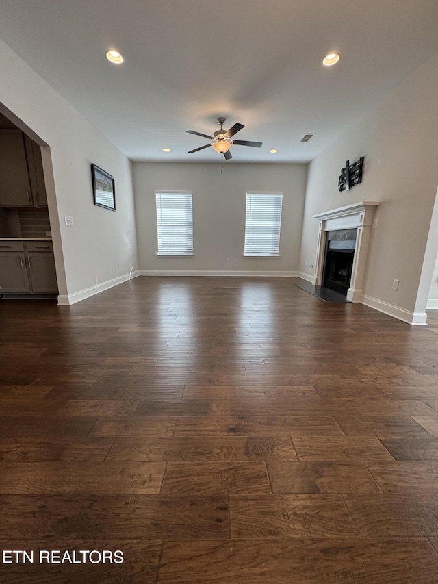 unfurnished living room with ceiling fan and dark wood-type flooring