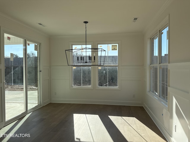 unfurnished dining area featuring dark wood-style floors, visible vents, crown molding, and a decorative wall