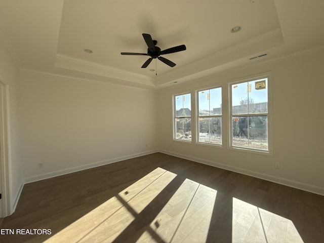 spare room featuring a tray ceiling, dark wood-style flooring, and visible vents