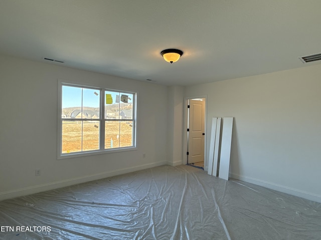 empty room featuring baseboards and visible vents