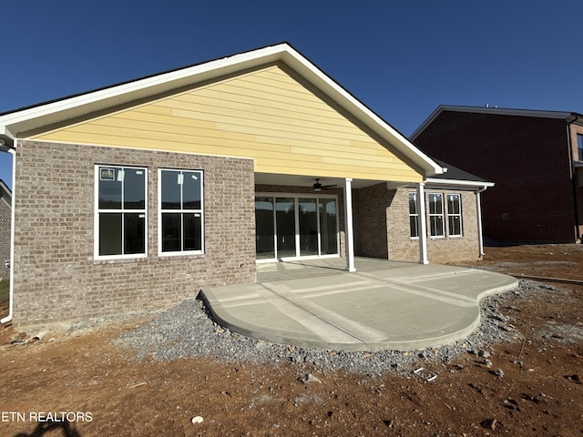 rear view of property with a ceiling fan, brick siding, and a patio