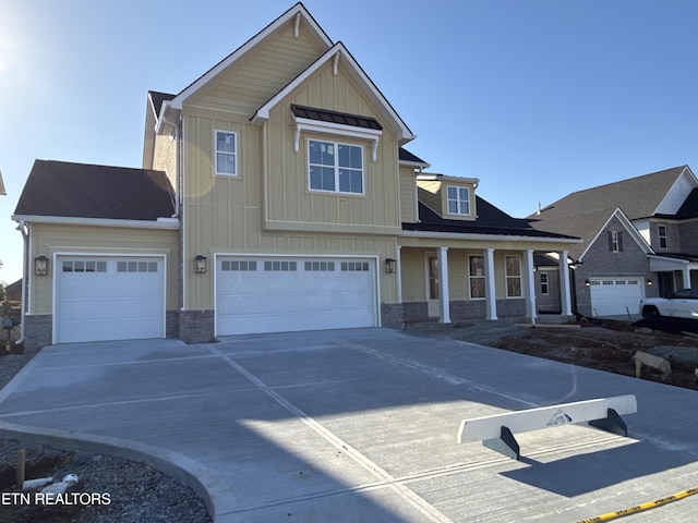 craftsman-style home featuring an attached garage, driveway, board and batten siding, and stone siding