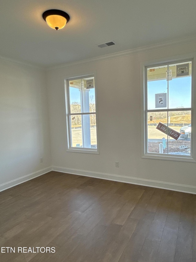 spare room featuring dark wood-style floors, baseboards, visible vents, and ornamental molding