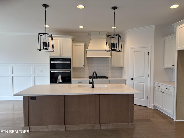 kitchen featuring multiple ovens, custom exhaust hood, light countertops, and ornamental molding