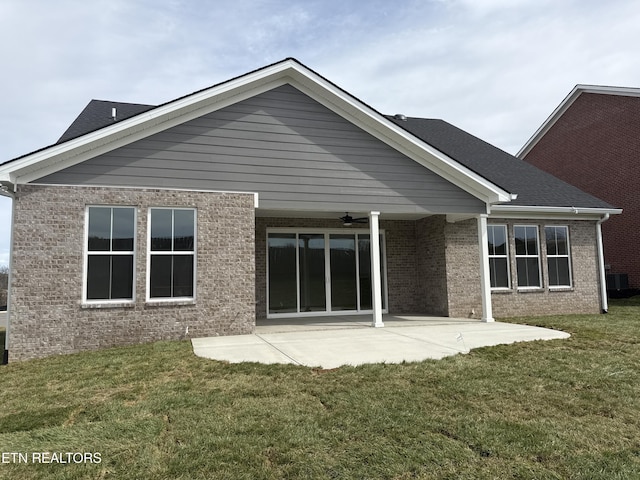 rear view of house featuring a lawn, ceiling fan, cooling unit, a patio area, and brick siding