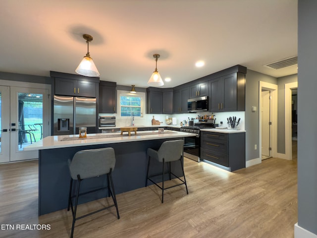 kitchen featuring light hardwood / wood-style floors, pendant lighting, appliances with stainless steel finishes, and a healthy amount of sunlight