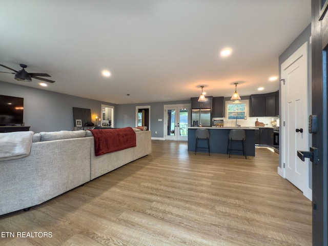 living room featuring ceiling fan, sink, light hardwood / wood-style flooring, and french doors