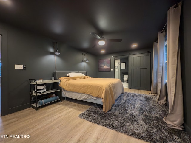 bedroom with light hardwood / wood-style floors, ceiling fan, and ensuite bath