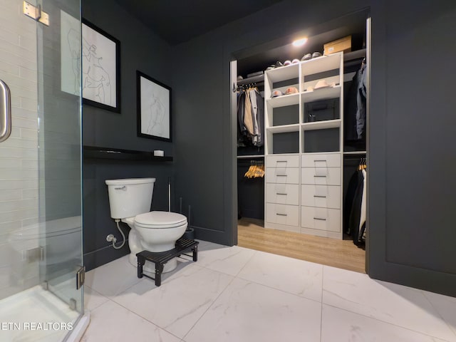 bathroom with toilet, an enclosed shower, and wood-type flooring