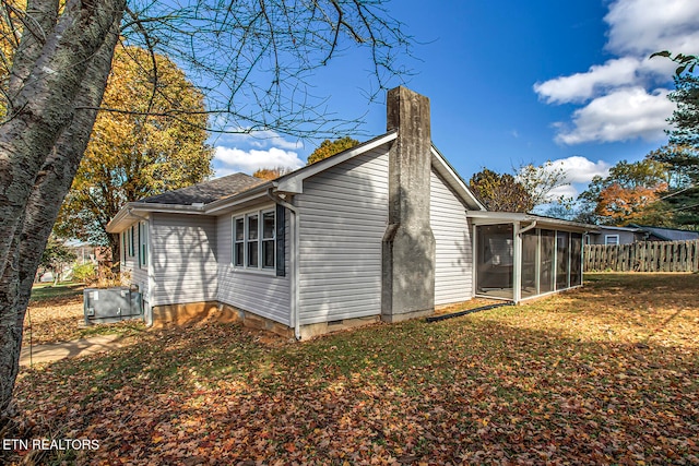 view of property exterior featuring central air condition unit and a sunroom