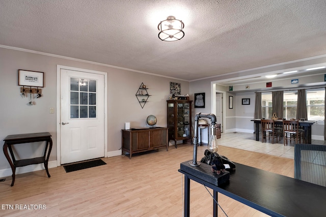 entrance foyer with light wood-type flooring, a textured ceiling, and crown molding