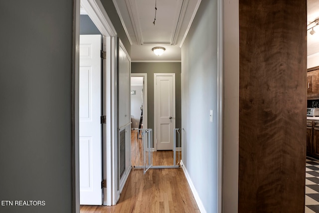 corridor featuring light wood-type flooring and ornamental molding