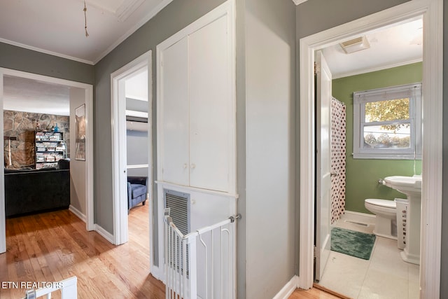 hall with ornamental molding and light wood-type flooring