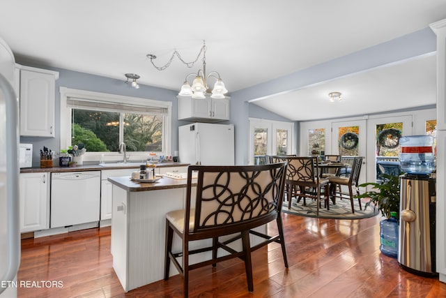 kitchen featuring white appliances, sink, lofted ceiling, dark wood-type flooring, and a breakfast bar area