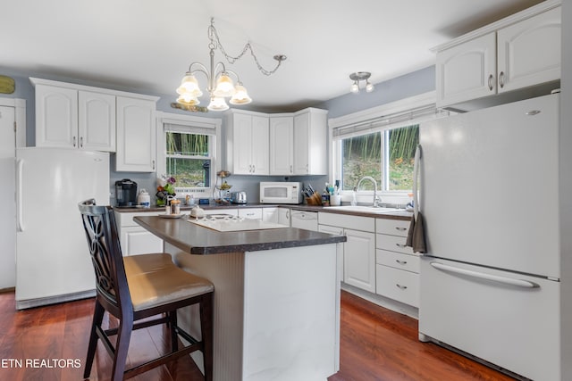 kitchen with white appliances, white cabinetry, and dark wood-type flooring