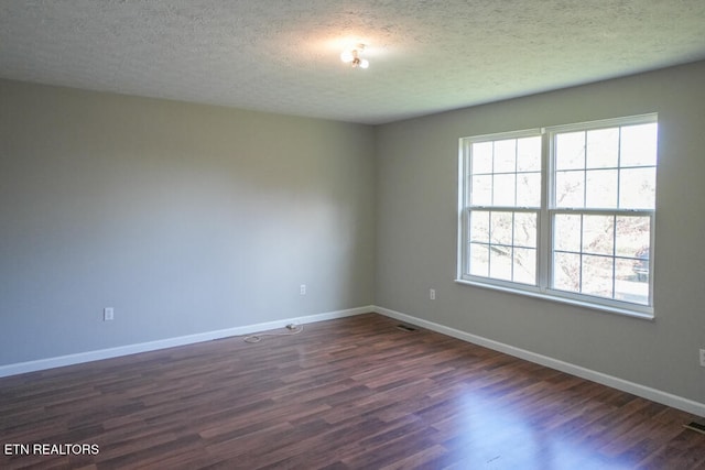 spare room featuring a textured ceiling and dark hardwood / wood-style floors