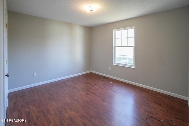 spare room with a textured ceiling and dark wood-type flooring