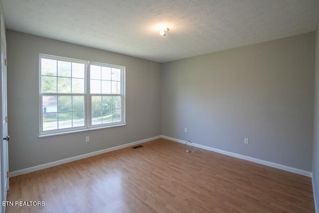 spare room with a textured ceiling and hardwood / wood-style flooring