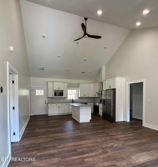 kitchen featuring a center island, stainless steel appliances, tasteful backsplash, high vaulted ceiling, and white cabinets