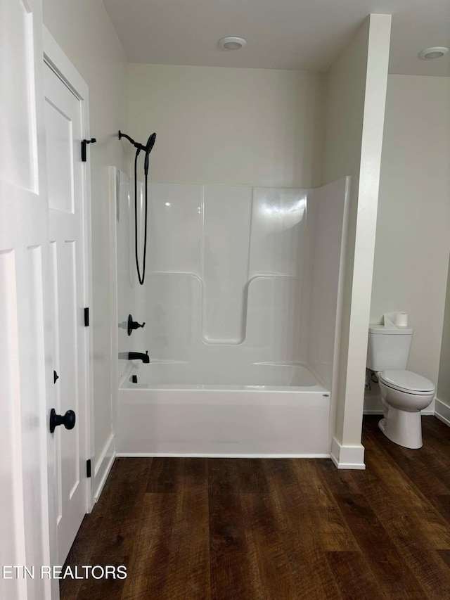 bathroom with hardwood / wood-style floors, shower / bathing tub combination, and toilet