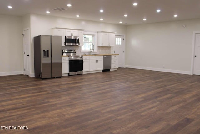 kitchen featuring white cabinetry, dark wood-type flooring, appliances with stainless steel finishes, and tasteful backsplash