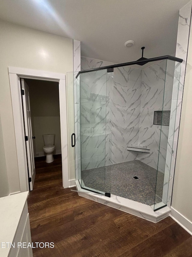 bathroom featuring hardwood / wood-style floors, toilet, and an enclosed shower