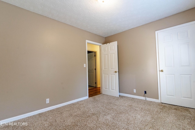 unfurnished bedroom featuring light colored carpet and a textured ceiling