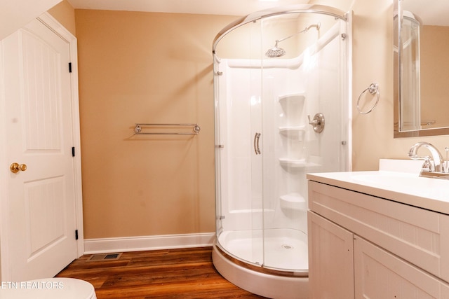 bathroom with hardwood / wood-style flooring, vanity, and a shower with door