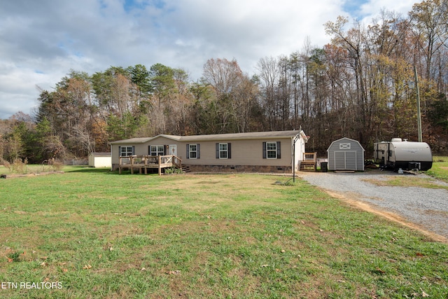 manufactured / mobile home with a storage unit, a wooden deck, and a front lawn