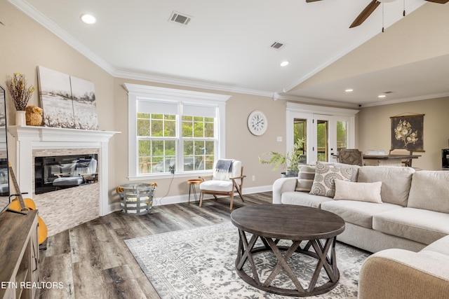 living room with a stone fireplace, a wealth of natural light, hardwood / wood-style floors, and lofted ceiling