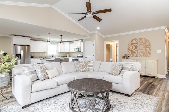 living room with ceiling fan, light hardwood / wood-style flooring, crown molding, and vaulted ceiling