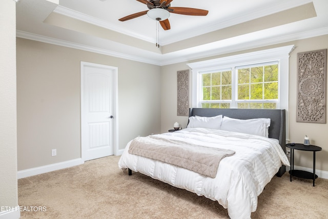 carpeted bedroom featuring a tray ceiling, ceiling fan, and crown molding