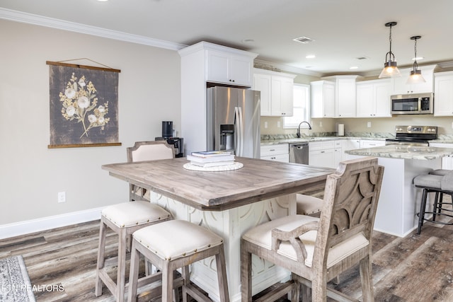 kitchen featuring white cabinetry, light stone counters, decorative light fixtures, and appliances with stainless steel finishes