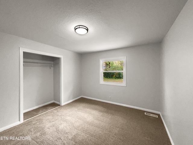 unfurnished bedroom featuring a closet, carpet, and a textured ceiling