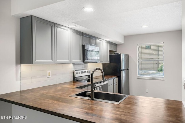 8709 Olde Colony Trl Unit 12, Knoxville, TN 37923 - kitchen featuring appliances with stainless steel finishes, wood counters, gray cabinets, decorative backsplash, and a textured ceiling