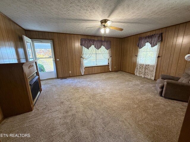 unfurnished living room with ceiling fan, a wealth of natural light, and light colored carpet