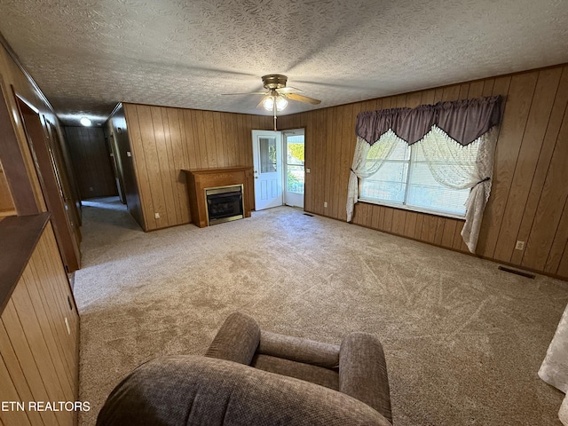 carpeted living room with wooden walls and ceiling fan