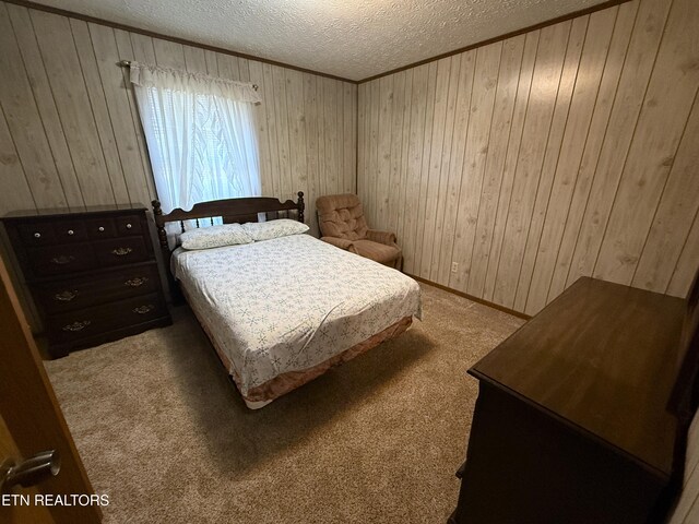 carpeted bedroom featuring wood walls and a textured ceiling