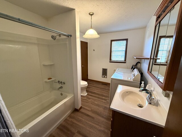 full bathroom with washing machine and clothes dryer, hardwood / wood-style floors, toilet, vanity, and tub / shower combination