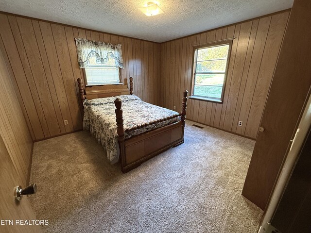 carpeted bedroom featuring a textured ceiling and wood walls