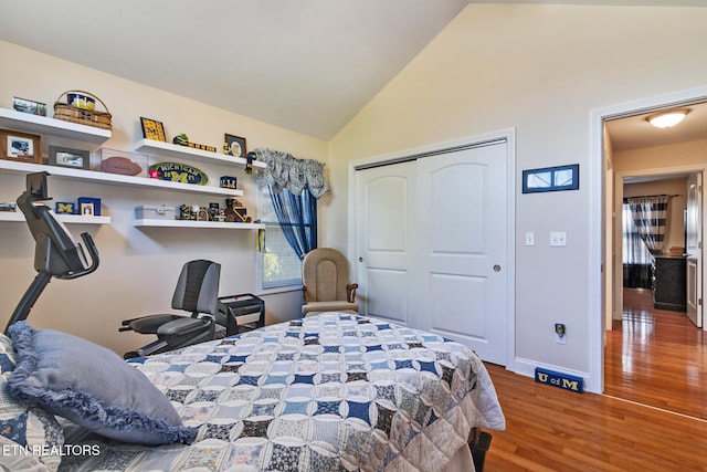 bedroom featuring high vaulted ceiling, a closet, baseboards, and wood finished floors