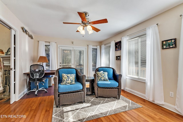 sitting room featuring a ceiling fan, plenty of natural light, baseboards, and wood finished floors